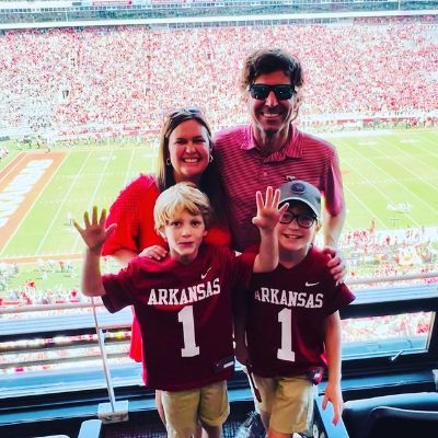 Bryan Sanders is wearing a red shirt. His wife is wearing red dress and his sons are wearing Kansas team jersey